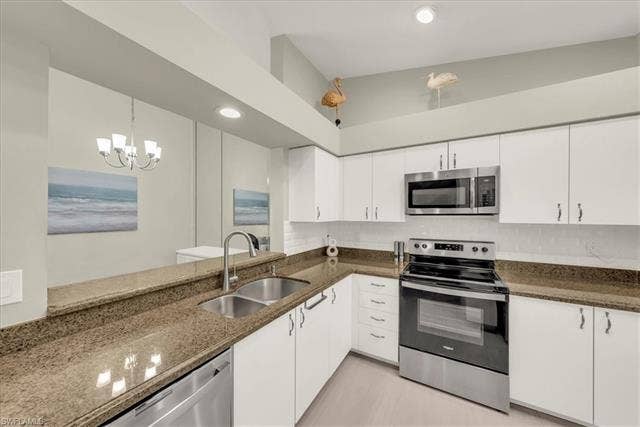 7320 Glenmoor Ln, #2304, Naples, FL 34104 Kitchen with stainless steel appliances, dark stone countertops, white cabinetry, decorative light fixtures, and recessed lighting