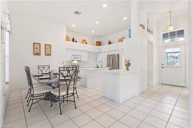 3650 Sunland Ln, Estero, FL 33928 Kitchen featuring a kitchen island, a high ceiling, light countertops, freestanding refrigerator, and white microwave
