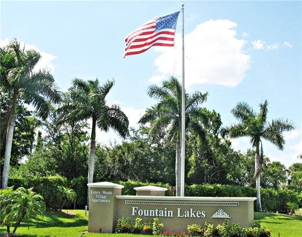 3650 Sunland Ln, Estero, FL 33928 Community / neighborhood sign featuring a yard and view of wooded area