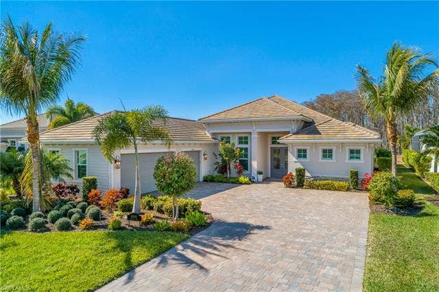 18500 Wildblue Blvd, Fort Myers, FL 33928 Single story home featuring a front lawn, decorative driveway, a tiled roof, and a garage