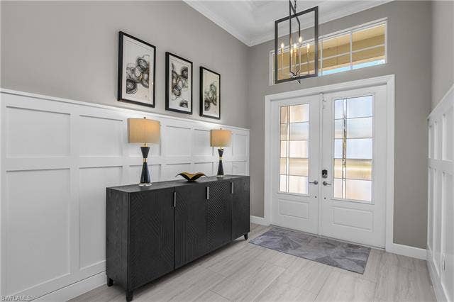 18500 Wildblue Blvd, Fort Myers, FL 33928 Entryway featuring french doors, a decorative wall, crown molding, and suspended lighting