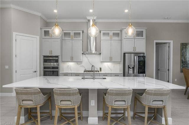 18500 Wildblue Blvd, Fort Myers, FL 33928 Kitchen with stainless steel appliances, a kitchen breakfast bar, backsplash, light stone counters, and a spacious island
