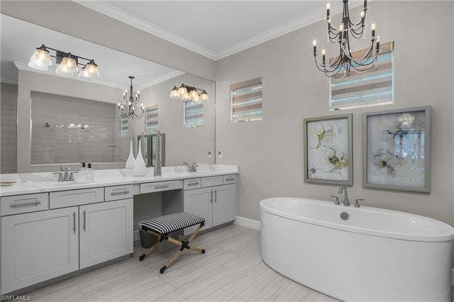 18500 Wildblue Blvd, Fort Myers, FL 33928 Bathroom with a chandelier, double vanity, a soaking tub, ornamental molding, and tiled shower