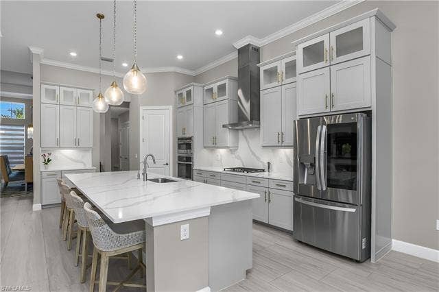 18500 Wildblue Blvd, Fort Myers, FL 33928 Kitchen with stainless steel appliances, glass fronted cabinets, decorative backsplash, a kitchen bar, and hanging light fixtures
