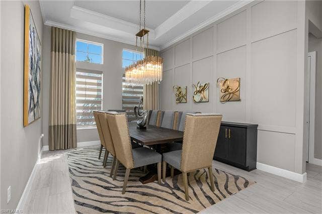18500 Wildblue Blvd, Fort Myers, FL 33928 Dining room featuring suspended lighting, a decorative wall, crown molding, and a tray ceiling