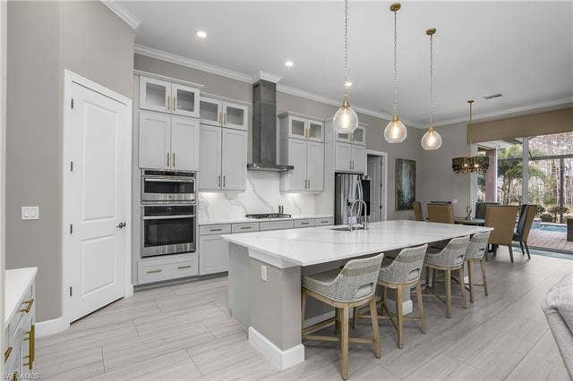18500 Wildblue Blvd, Fort Myers, FL 33928 Kitchen with a breakfast bar area, crown molding, a kitchen island with sink, stainless steel appliances, and a chandelier
