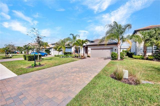 18298 Ridgeline Dr, Estero, FL 33928 View of front of house featuring decorative driveway, a front lawn, stucco siding, and a garage