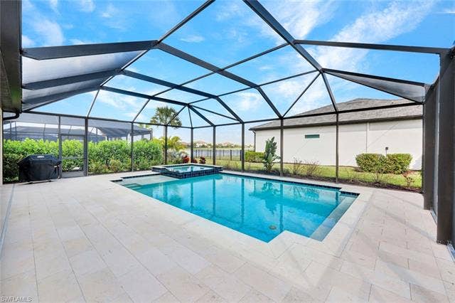 18298 Ridgeline Dr, Estero, FL 33928 Combined pool / hot tub with a sunroom, a patio area, a lanai, and a grill