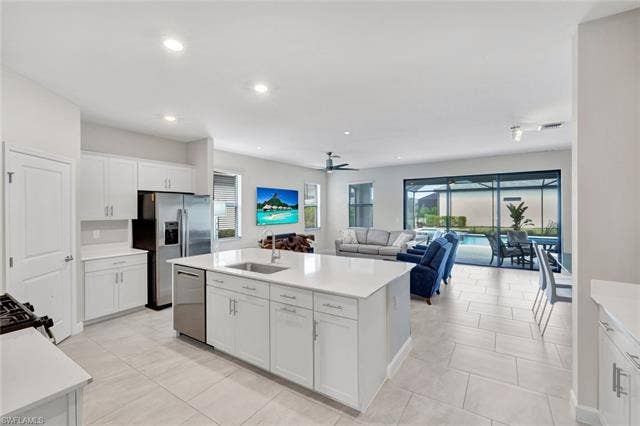 18298 Ridgeline Dr, Estero, FL 33928 Kitchen with white cabinets, a center island with sink, dishwasher, ceiling fan, and open floor plan