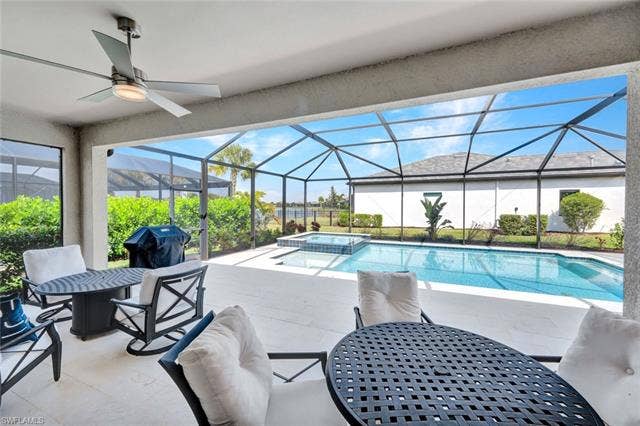 18298 Ridgeline Dr, Estero, FL 33928 Combined pool / hot tub featuring a patio, a sunroom, a lanai, outdoor dining area, and a grill