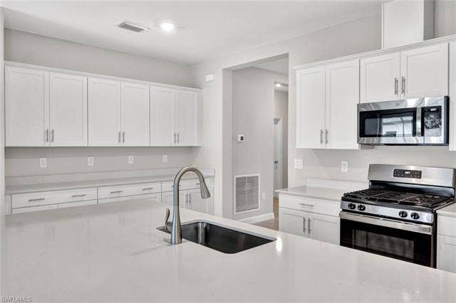 18298 Ridgeline Dr, Estero, FL 33928 Kitchen featuring stainless steel appliances, white cabinets, and light stone countertops