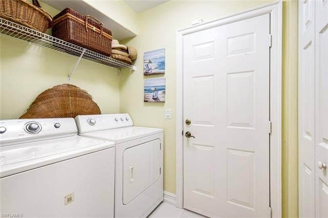 20667 Wildcat Run Dr, #101, Estero, FL 33928 Laundry area with independent washer and dryer and light tile patterned floors