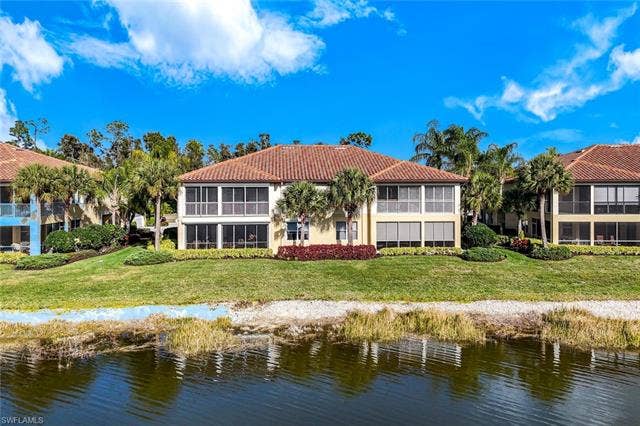 20667 Wildcat Run Dr, #101, Estero, FL 33928 Rear view of property with a tile roof, a water view, stucco siding, and a yard