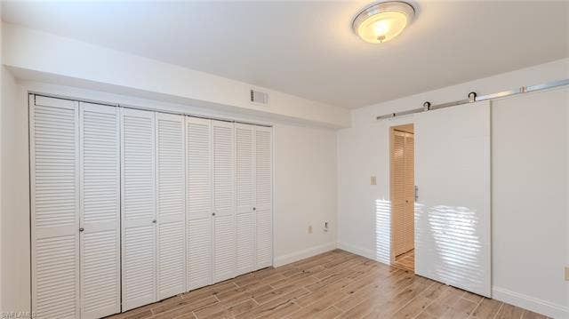 3160 Seasons Way, #709, Estero, FL 33928 Unfurnished bedroom featuring wood tiled floors and a barn door