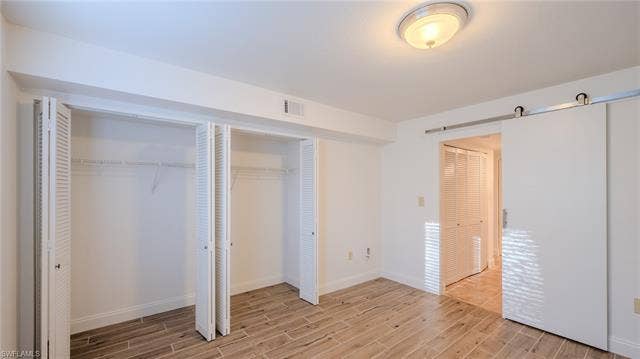 3160 Seasons Way, #709, Estero, FL 33928 Unfurnished bedroom with a barn door, wood tiled floors, and multiple closets