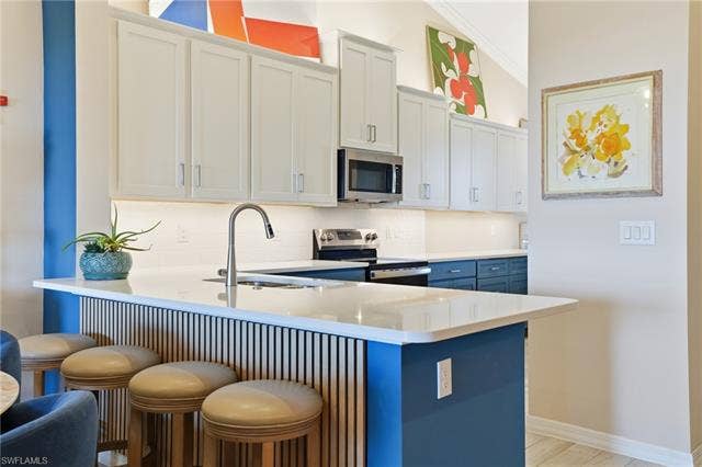 11861 Venetian Lagoon Dr, #203, Fort Myers, FL 33913 Kitchen with a breakfast bar, a peninsula, stainless steel appliances, and tasteful backsplash