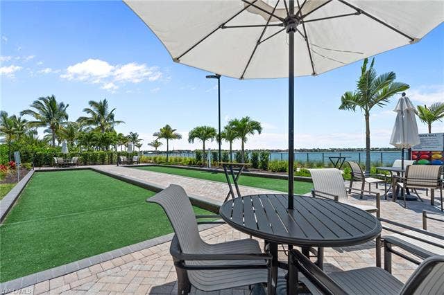 11861 Venetian Lagoon Dr, #203, Fort Myers, FL 33913 View of patio featuring a game area, a water view, and outdoor dining space