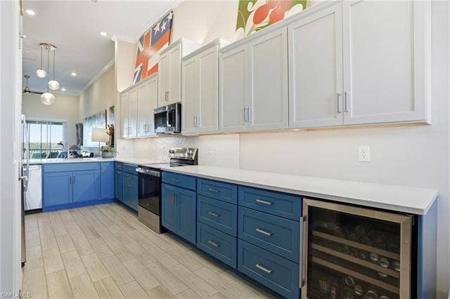 11861 Venetian Lagoon Dr, #203, Fort Myers, FL 33913 Two tone kitchen featuring stainless steel appliances, beverage cooler, two tone color scheme, crown molding, and hanging light fixtures