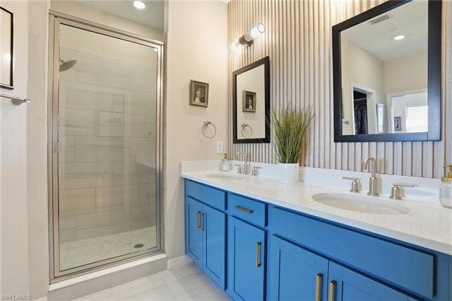 11861 Venetian Lagoon Dr, #203, Fort Myers, FL 33913 Bathroom with double vanity, a shower stall, recessed lighting, light tile patterned flooring, and wallpapered walls