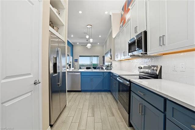11861 Venetian Lagoon Dr, #203, Fort Myers, FL 33913 Dual tone kitchen with stainless steel appliances, decorative light fixtures, wood tiled floors, dual tone cabinets, and tasteful backsplash