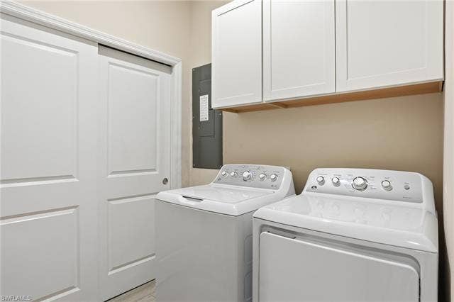 11861 Venetian Lagoon Dr, #203, Fort Myers, FL 33913 Laundry area with electric panel, washing machine and dryer, and cabinet space