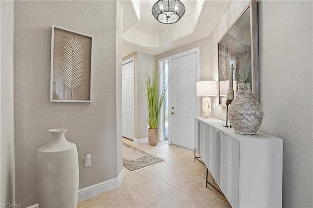 19620 Marino Lake Cir, #2802, Miromar Lakes, FL 33913 Foyer entrance with a textured wall, a tray ceiling, and light tile patterned flooring
