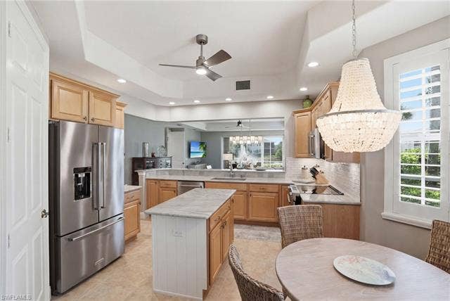 19620 Marino Lake Cir, #2802, Miromar Lakes, FL 33913 Kitchen featuring a peninsula, stainless steel appliances, a ceiling fan, a center island, and light wood finish cabinetry