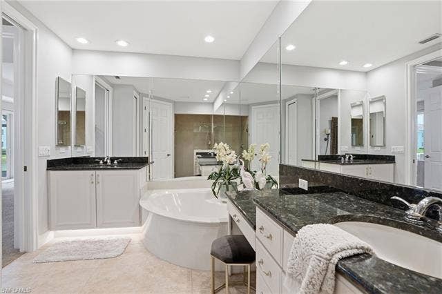 19620 Marino Lake Cir, #2802, Miromar Lakes, FL 33913 Full bathroom featuring two vanities, light tile patterned floors, a tub, and a closet