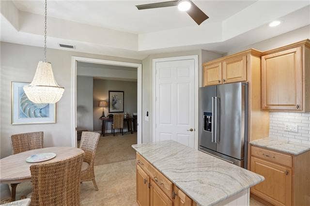 19620 Marino Lake Cir, #2802, Miromar Lakes, FL 33913 Kitchen with high quality fridge, a ceiling fan, light wood finish cabinets, light stone countertops, and tasteful backsplash