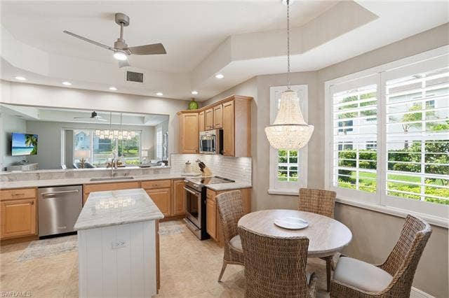 19620 Marino Lake Cir, #2802, Miromar Lakes, FL 33913 Kitchen with a chandelier, stainless steel appliances, decorative backsplash, light wood finish cabinetry, and a kitchen island