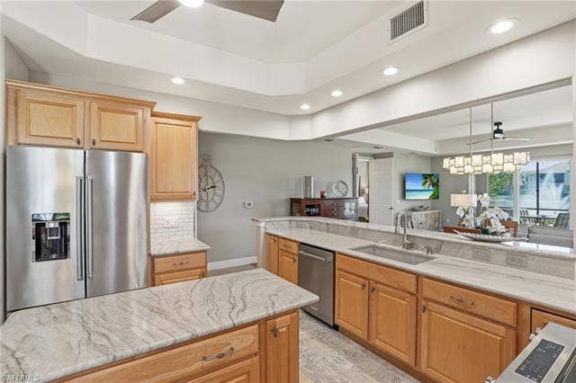 19620 Marino Lake Cir, #2802, Miromar Lakes, FL 33913 Kitchen featuring ceiling fan, stainless steel appliances, a raised ceiling, open floor plan, and light wood finish cabinetry