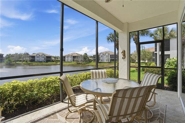 19620 Marino Lake Cir, #2802, Miromar Lakes, FL 33913 Sunroom featuring a water view, a residential view, a textured wall, and stone finish floors