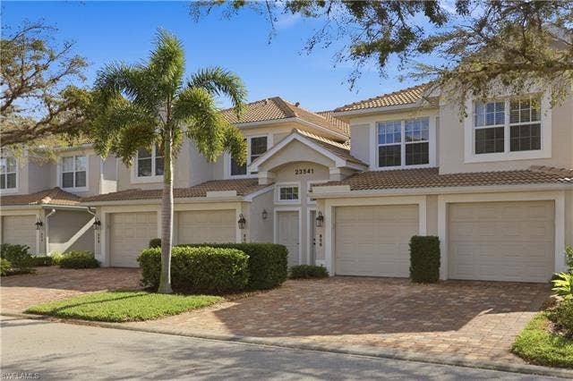23541 Sandycreek Ter, #806, Estero, FL 34135 Mediterranean / spanish-style home featuring an attached garage, a tile roof, driveway, and stucco siding