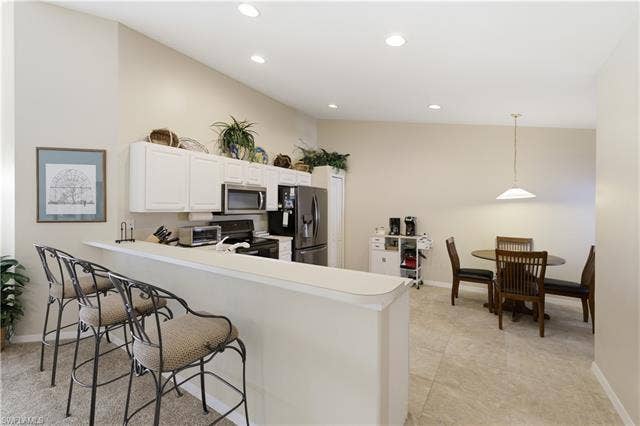 23541 Sandycreek Ter, #806, Estero, FL 34135 Kitchen with a breakfast bar, stainless steel appliances, light countertops, a peninsula, and white cabinetry