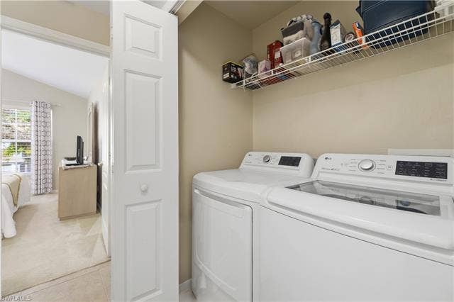 23541 Sandycreek Ter, #806, Estero, FL 34135 Laundry area with lofted ceiling, independent washer and dryer, light carpet, and light tile patterned floors
