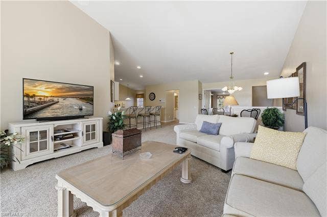 23541 Sandycreek Ter, #806, Estero, FL 34135 Living area featuring hanging lights, a high ceiling, and light carpet
