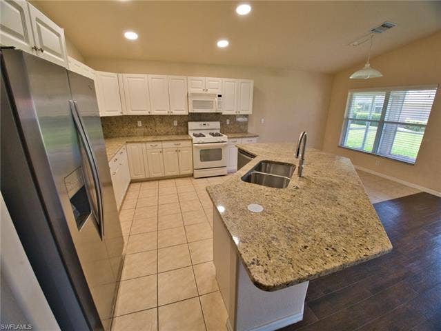 9071 Astonia Way, Estero, FL 33967 Kitchen featuring a large central island with a double stainless steel sink and a gooseneck faucet