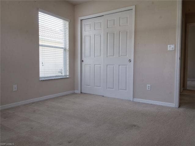 9071 Astonia Way, Estero, FL 33967 Bedroom featuring neutral-toned carpeting, a window with horizontal blinds, and a closet with white bi-fold doors