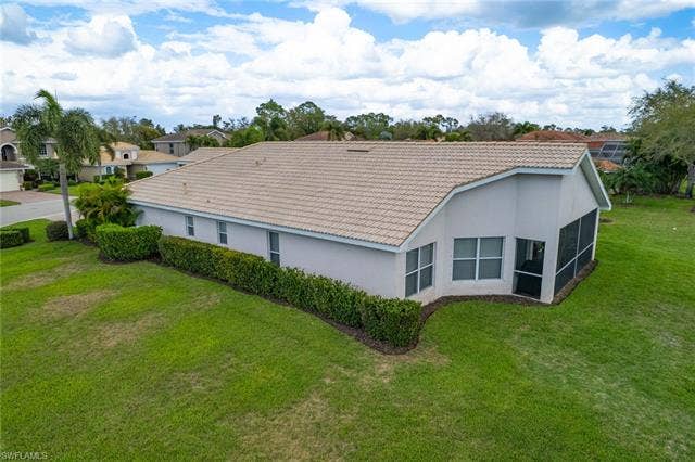 9071 Astonia Way, Estero, FL 33967 Back of property featuring a tiled roof, stucco siding, a yard, and a sunroom