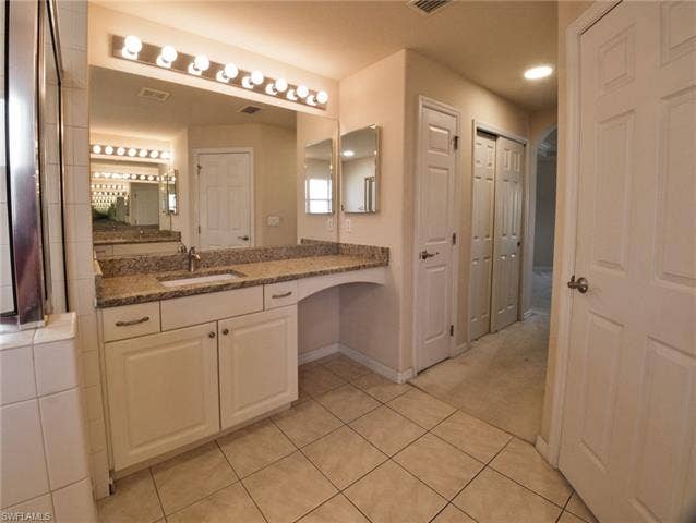 9071 Astonia Way, Estero, FL 33967 Bathroom vanity featuring a speckled countertop, integrated sink, and full-width mirror with overhead lighting