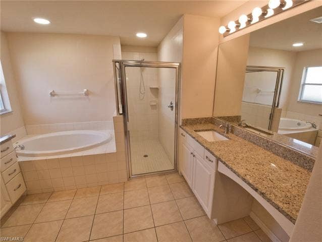 9071 Astonia Way, Estero, FL 33967 Bathroom featuring a tiled floor, a built-in soaking tub with tiled surround, a glass-enclosed shower, a vanity with a white basin sink, and a granite-finish countertop