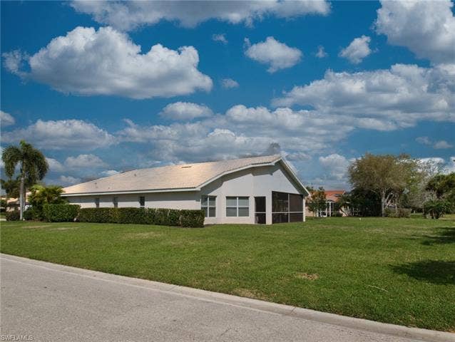9071 Astonia Way, Estero, FL 33967 View of home's exterior with a lawn, stucco siding, a tiled roof, and a sunroom
