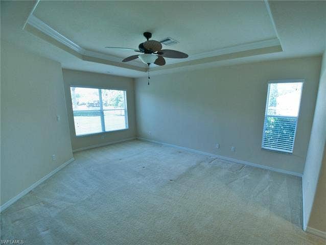 9071 Astonia Way, Estero, FL 33967 Spacious room featuring a tray ceiling with crown molding, a ceiling fan, and carpeted flooring