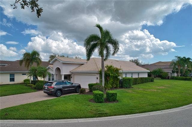 9071 Astonia Way, Estero, FL 33967 View of front of property with a front lawn, a tiled roof, an attached garage, decorative driveway, and stucco siding