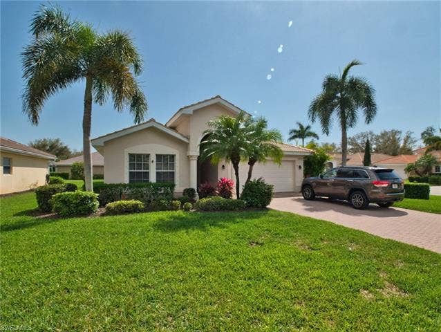9071 Astonia Way, Estero, FL 33967 View of front facade with decorative driveway, an attached garage, a front yard, and stucco siding