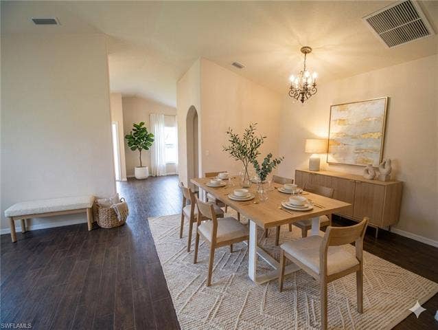 9071 Astonia Way, Estero, FL 33967 Dining area featuring vaulted ceilings, dark wood-finish flooring, an arched doorway, and a brass chandelier