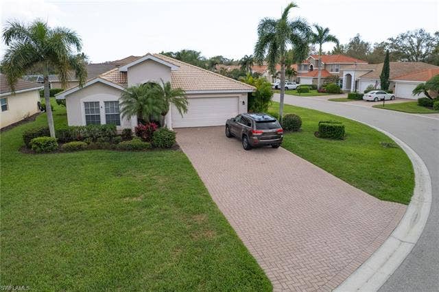 9071 Astonia Way, Estero, FL 33967 Mediterranean / spanish-style house with decorative driveway, a front lawn, an attached garage, stucco siding, and a residential view