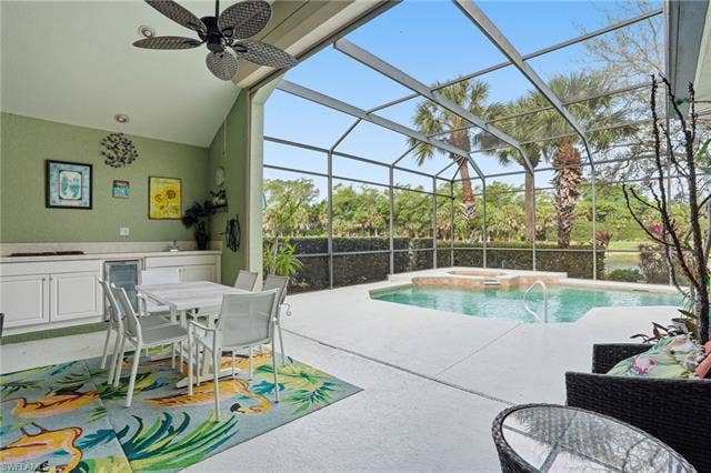 17801 Modena Rd, Miromar Lakes, FL 33913 Integrated pool / hot tub with a sunroom, glass enclosure, a patio area, and outdoor dining area
