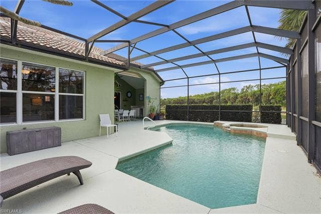 17801 Modena Rd, Miromar Lakes, FL 33913 Integrated pool / spa featuring a sunroom, a lanai, and a patio