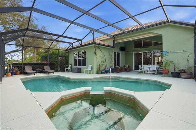 17801 Modena Rd, Miromar Lakes, FL 33913 Relaxing pool / spa featuring a sunroom, outdoor dining space, a lanai, and a patio area